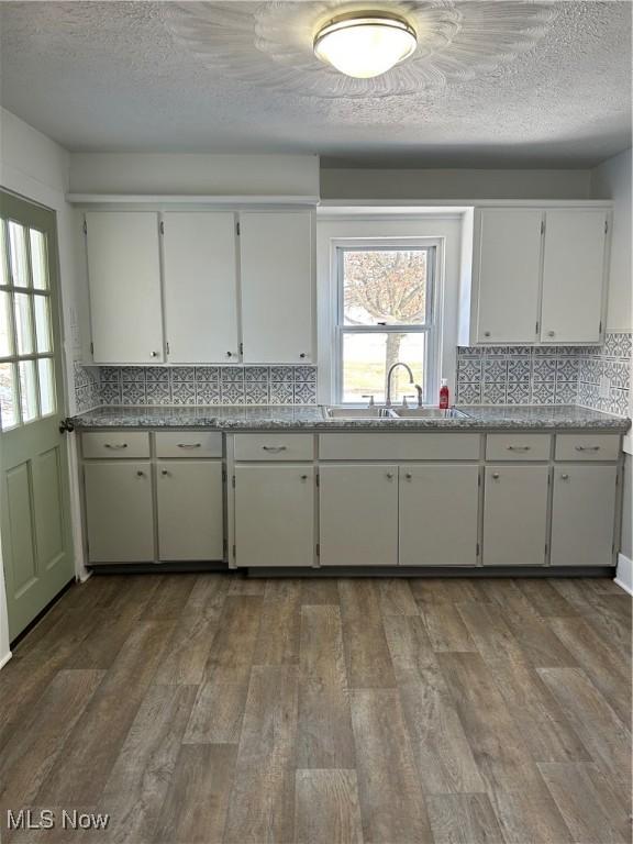 kitchen with light countertops, wood finished floors, a sink, and decorative backsplash