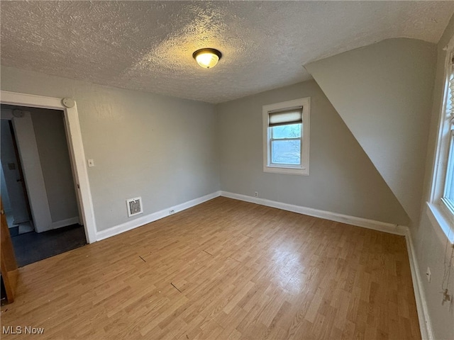 spare room with wood finished floors, visible vents, and baseboards