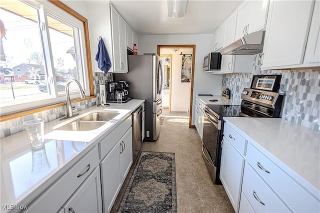 kitchen with appliances with stainless steel finishes, light countertops, white cabinets, and under cabinet range hood