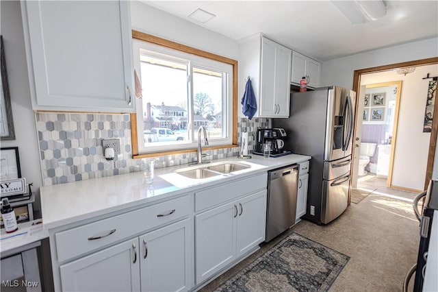 kitchen with white cabinets, a sink, stainless steel appliances, light countertops, and backsplash