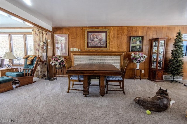 dining room featuring wooden walls and light colored carpet