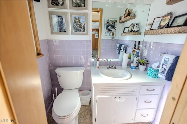 half bathroom featuring toilet, a wainscoted wall, vanity, and tile walls