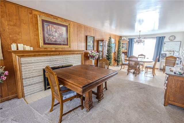 dining room with a chandelier, light carpet, wood walls, and light tile patterned flooring