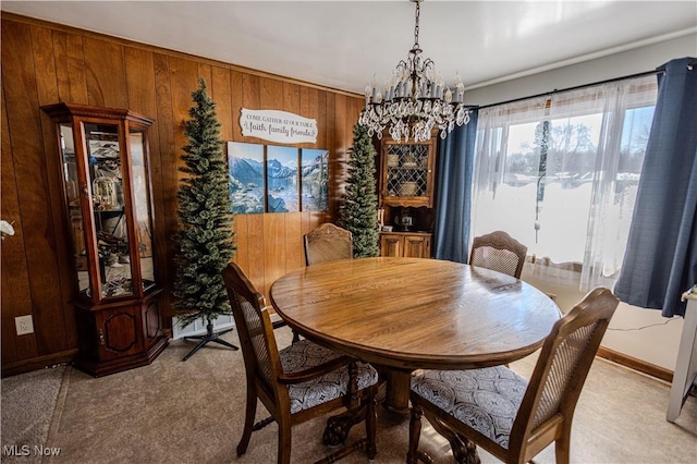 dining space featuring light carpet, wood walls, baseboards, and a chandelier