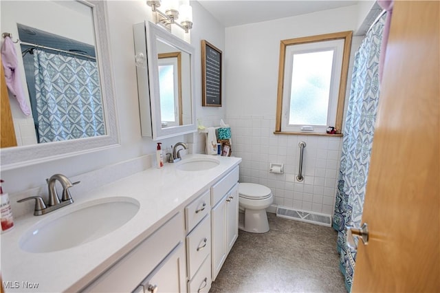 full bathroom featuring double vanity, wainscoting, a sink, and tile walls