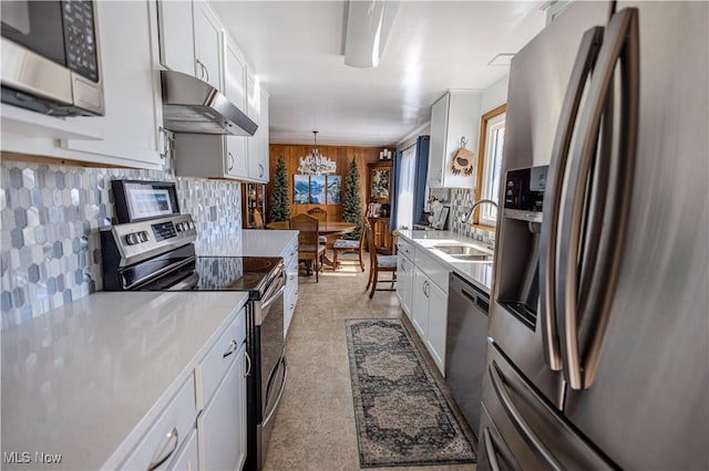 kitchen with under cabinet range hood, white cabinetry, appliances with stainless steel finishes, and light countertops