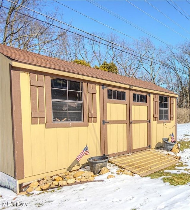 snow covered structure with a storage unit and an outdoor structure