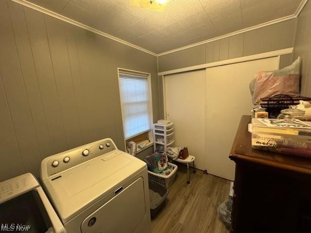 laundry area featuring laundry area, ornamental molding, wood finished floors, and washing machine and clothes dryer