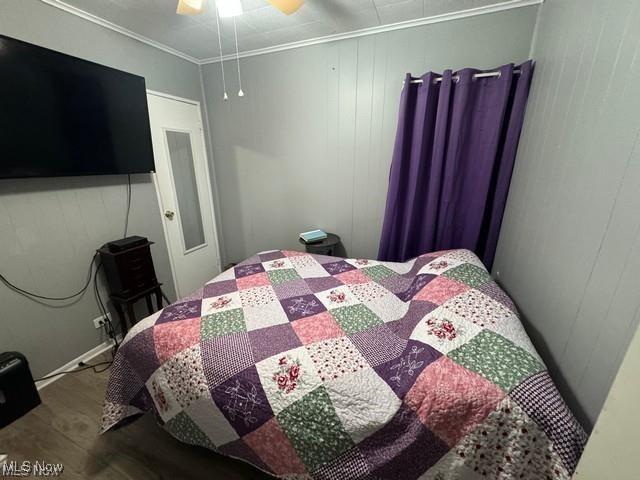 bedroom featuring wood finished floors, a ceiling fan, and crown molding