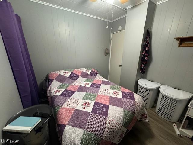 bedroom featuring ceiling fan, crown molding, and wood finished floors