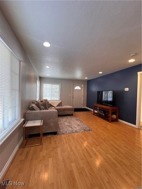 living room featuring recessed lighting, visible vents, a textured ceiling, light wood-type flooring, and baseboards