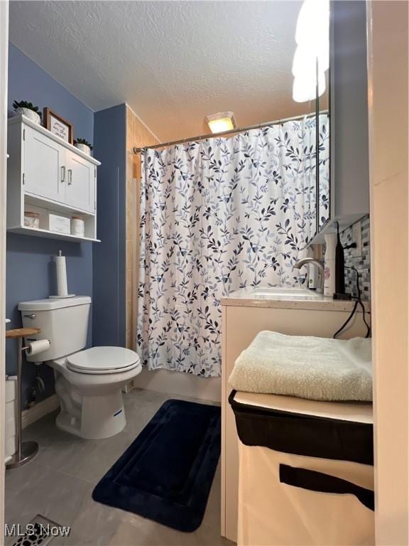 full bathroom with a textured ceiling, vanity, toilet, and tile patterned floors