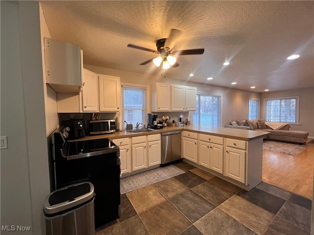 kitchen with plenty of natural light, appliances with stainless steel finishes, open floor plan, a peninsula, and a sink