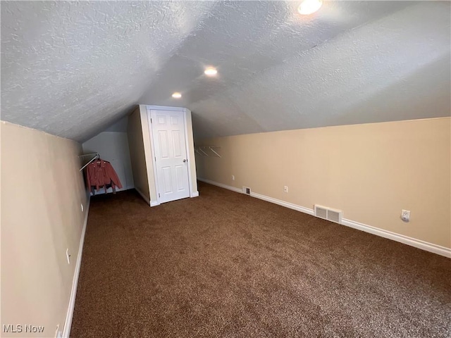 bonus room featuring vaulted ceiling, a textured ceiling, visible vents, and baseboards