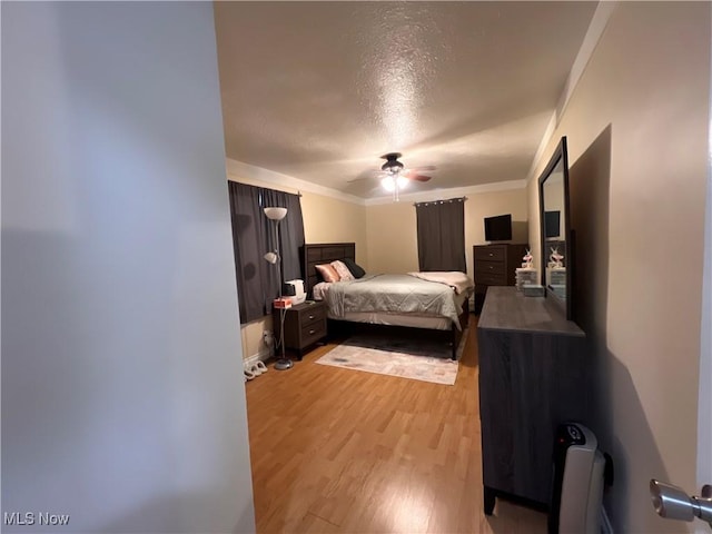 bedroom with light wood-style floors, a ceiling fan, and crown molding