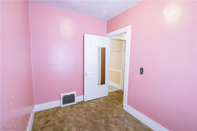 carpeted spare room featuring visible vents and baseboards