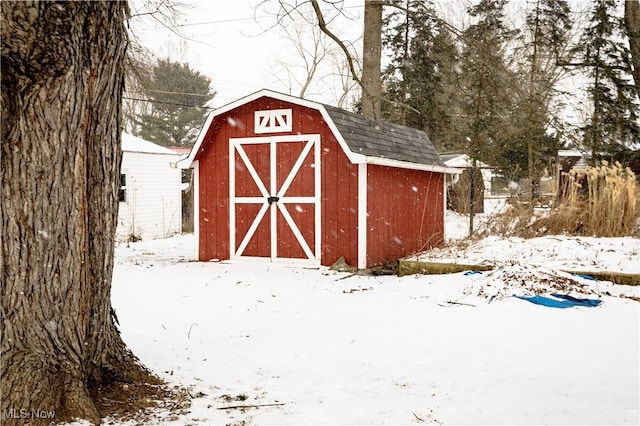 snow covered structure featuring an outbuilding and a storage shed