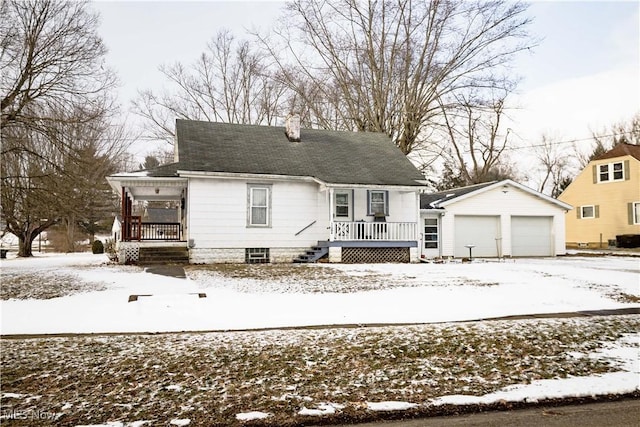 view of front of home featuring a garage, a chimney, a porch, and an outbuilding