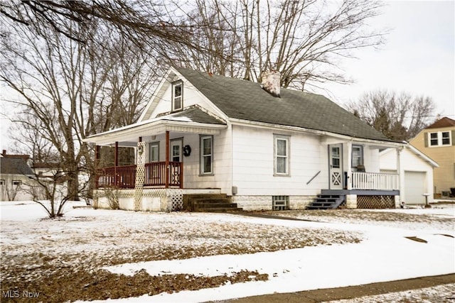 view of front of property with covered porch, a shingled roof, a chimney, and a detached garage