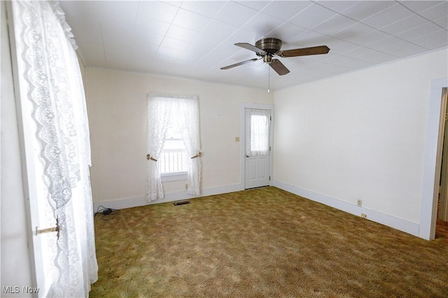 carpeted empty room with baseboards, visible vents, and a ceiling fan