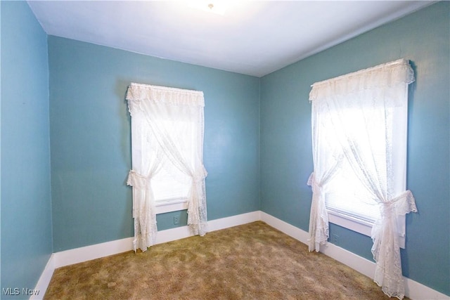 carpeted empty room featuring baseboards