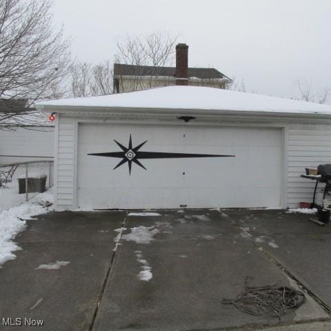 snow covered garage with a detached garage