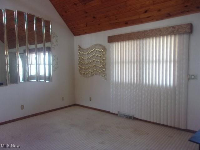 carpeted spare room with lofted ceiling, wooden ceiling, visible vents, and baseboards