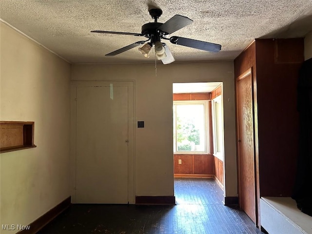 interior space with a ceiling fan, baseboards, and a textured ceiling