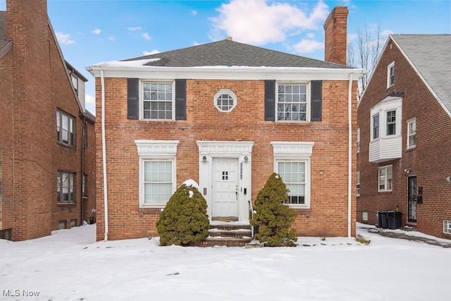 view of front facade featuring a chimney, cooling unit, and brick siding