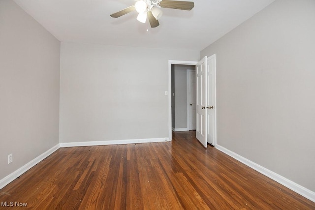 spare room with a ceiling fan, dark wood-style flooring, and baseboards