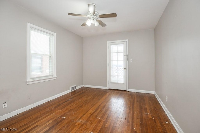 empty room featuring dark wood-style floors, baseboards, visible vents, and a ceiling fan