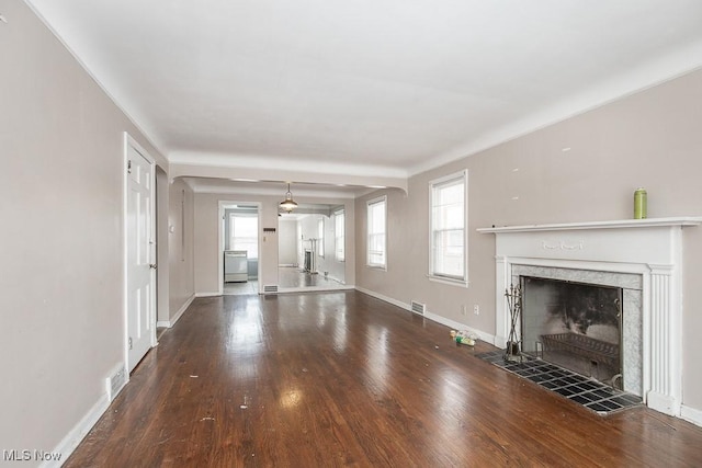 unfurnished living room featuring a healthy amount of sunlight, a premium fireplace, and dark wood finished floors