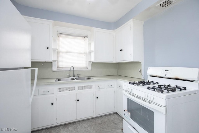 kitchen with light countertops, white appliances, a sink, and white cabinetry