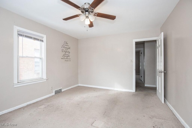 spare room featuring ceiling fan, light colored carpet, visible vents, and baseboards