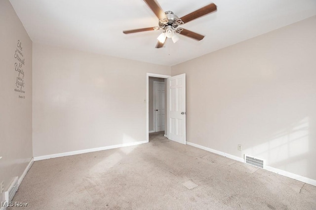 carpeted spare room featuring baseboards, visible vents, and ceiling fan