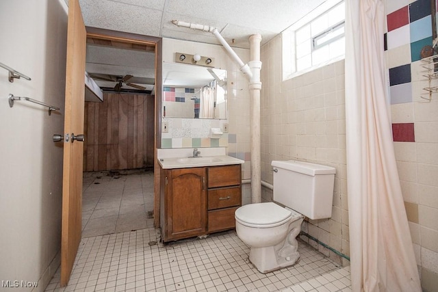 bathroom with tile patterned flooring, vanity, toilet, and tile walls