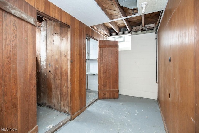 interior space featuring concrete flooring, concrete block wall, and wooden walls