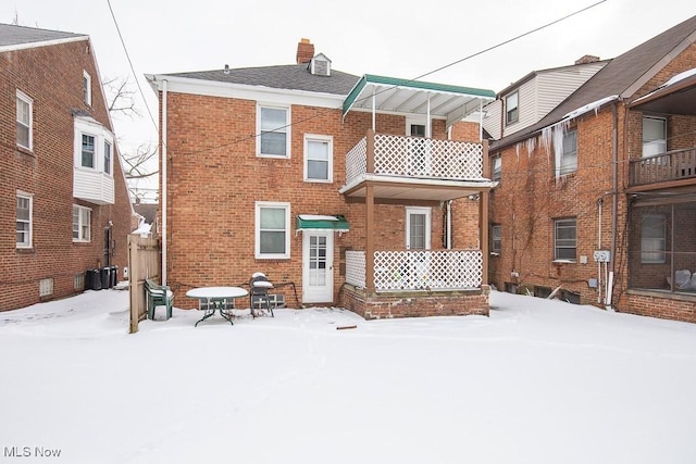 snow covered house with brick siding and a chimney