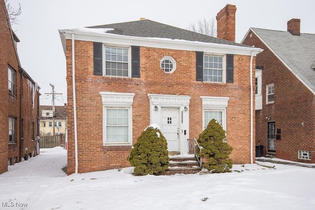 view of front of home with brick siding and a chimney