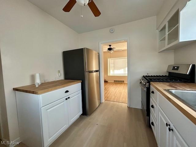 kitchen featuring light wood-style flooring, butcher block counters, white cabinetry, appliances with stainless steel finishes, and open shelves