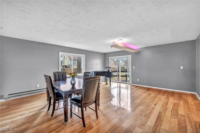 dining room featuring a baseboard heating unit, baseboards, light wood-style flooring, and a healthy amount of sunlight