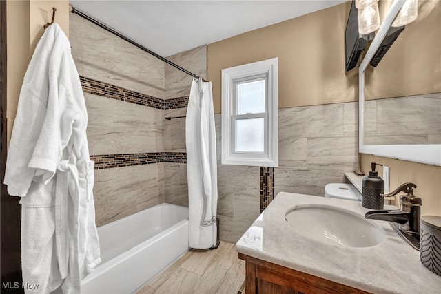 bathroom featuring shower / tub combo, wainscoting, tile walls, and vanity