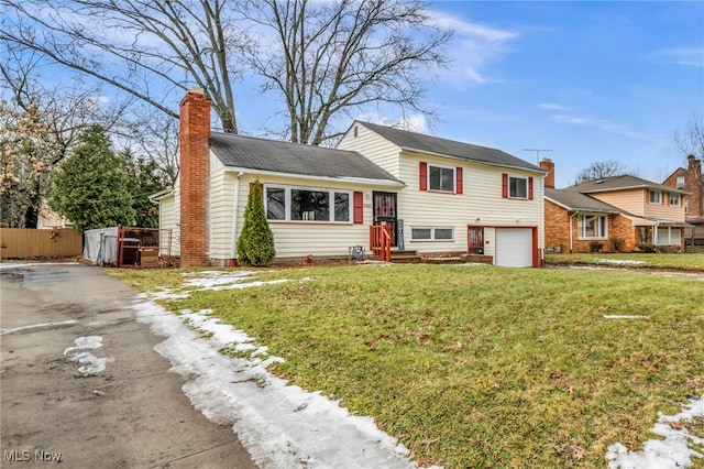 split level home with driveway, a front yard, fence, and a chimney