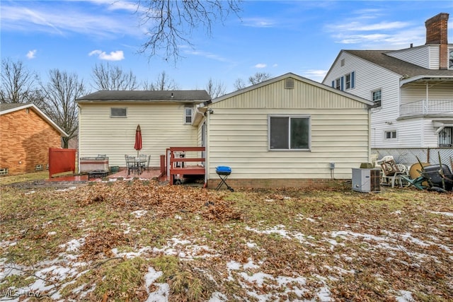 snow covered rear of property featuring cooling unit and fence