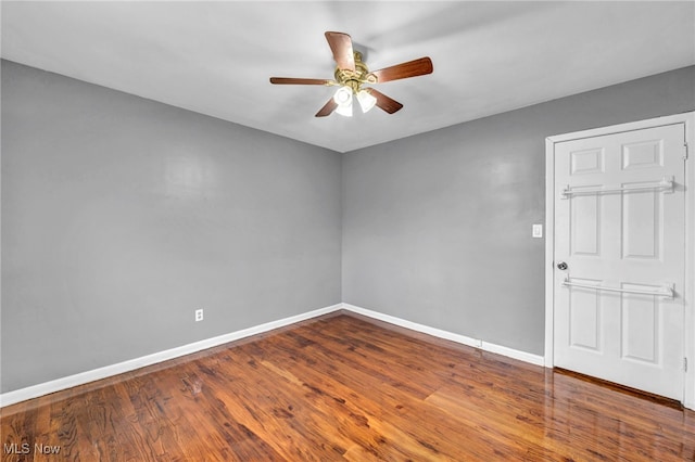 spare room with wood finished floors, a ceiling fan, and baseboards