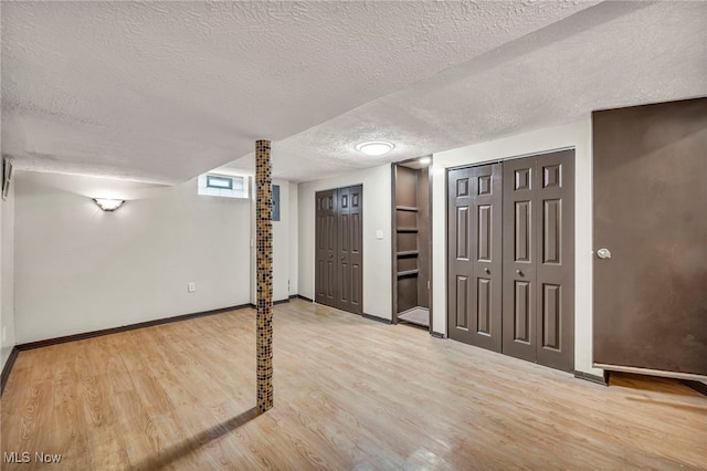 basement with a textured ceiling, wood finished floors, and baseboards