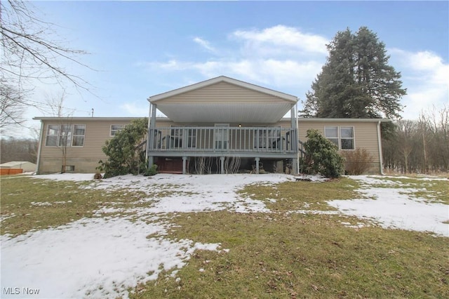 snow covered rear of property featuring covered porch and a lawn