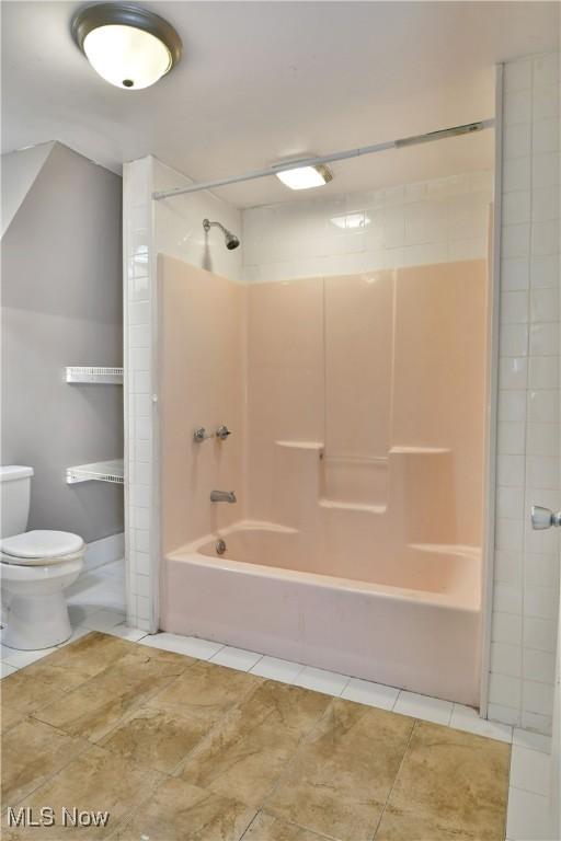 bathroom with washtub / shower combination, tile patterned flooring, and toilet