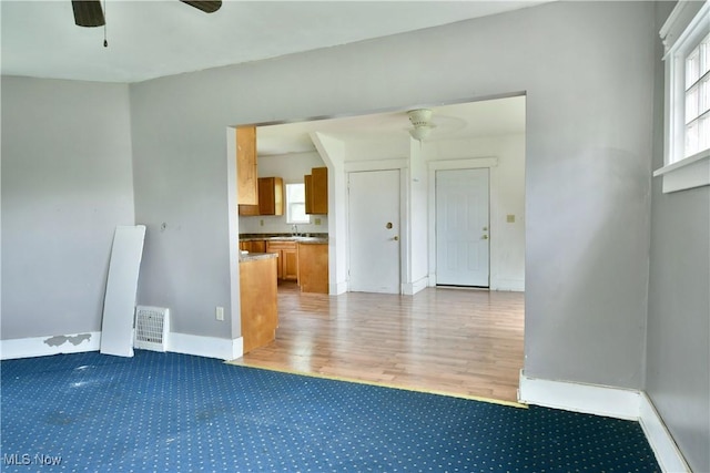 spare room with light wood-style floors, ceiling fan, visible vents, and a sink