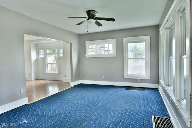 unfurnished room featuring plenty of natural light, visible vents, and baseboards